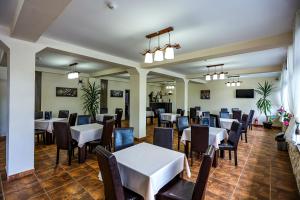 uma sala de jantar com mesas e cadeiras brancas em Casa Celestin em Eşelniţa