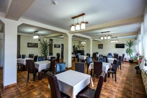 a dining room with white tables and chairs at Pensiunea Celestin in Eşelniţa