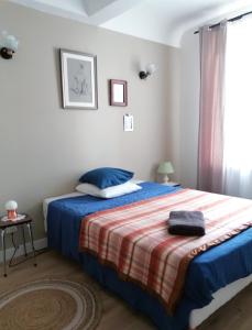 ein Schlafzimmer mit einem Bett mit einer blauen Decke und einem Fenster in der Unterkunft Charmante suite indépendante en maison de village in Loriol-sur-Drôme