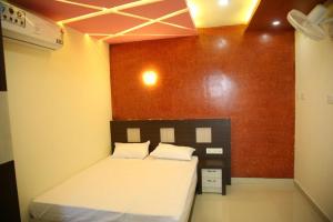 a bedroom with a bed and a red wall at City Tower Lodge in Nilambūr +2 photos