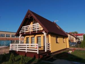 a small yellow house with a brown roof at Domki Grażyna in Jastarnia