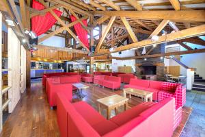 un restaurant avec des canapés rouges et des tables dans une salle dans l'établissement Village Club Les Tavaillons, aux Carroz d'Arâches