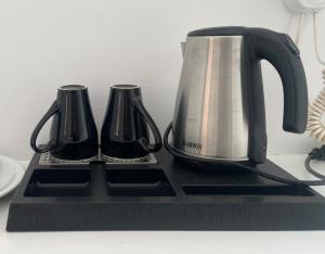 a tea kettle and two cups on a black tray at La Villa Rooms in Mikonos