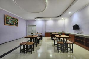 a room with tables and chairs and a flat screen tv at Urbanview Hotel Mutiara Persada Syariah Majalengka by RedDoorz 