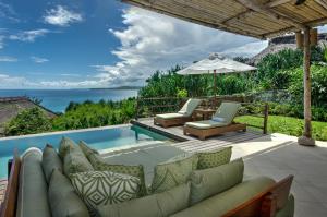 a patio with a couch and chairs next to a swimming pool at NIHI Sumba in Watukarere