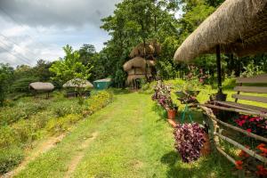 a garden with a bench and flowers and a thatch roof at Zyamadhari in Mananthavady