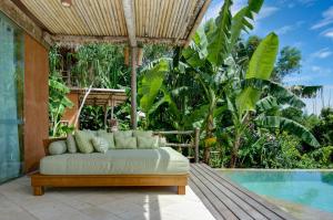 a bed sitting on a porch next to a pool at NIHI Sumba in Watukarere