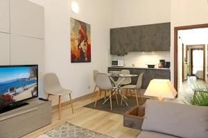 sala de estar con TV y mesa con sillas en Appartamenti Alighieri, en Bardolino