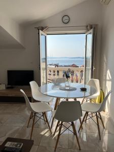 a dining room with a table and chairs and a large window at Apartments Goga in Vodice