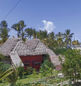 una casa antigua con techo de paja y palmeras en Mamarasta, en Bwejuu