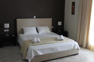 a bedroom with a large white bed with slippers on it at Diavlos Studios in Agiokampos