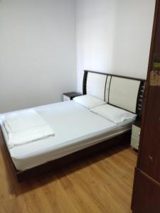 a bed in a room with white sheets and a wooden floor at HP Vacation Marina Court in Kota Kinabalu