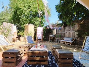 a patio with a table and chairs and logs at Le Bivouac in Cabariot