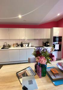 a kitchen with white cabinets and flowers on a table at Sublime waterfront retreat with private terrace in Bristol
