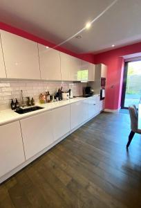 una cucina con armadietti bianchi e parete rossa di Sublime waterfront retreat with private terrace a Bristol