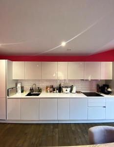 a kitchen with white cabinets and a red wall at Sublime waterfront retreat with private terrace in Bristol