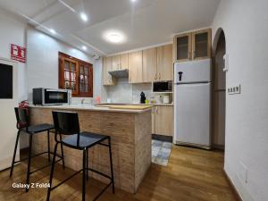- une cuisine avec un réfrigérateur blanc et deux tabourets de bar dans l'établissement VILLA ARTEP Lujoso apartamento con piscina comunitaria, à Carthagène