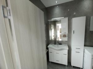 y baño con lavabo blanco y espejo. en Apartmani Vasković, en Trebinje