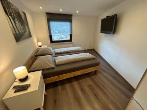 1 dormitorio con 2 camas, escritorio y TV en Ferienwohnung Ahrblick, en Schuld