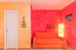 Casa Maria 250m From The Beach - Happy Rentals في بورتو بوزو: كرسي برتقالي في غرفة بجدران حمراء