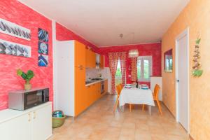 kuchnia z czerwonymi ścianami i stołem z kuchenką mikrofalową w obiekcie Casa Maria 250m From The Beach - Happy Rentals w mieście Porto Pozzo
