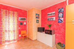 salon z czerwonymi ścianami i telewizorem w obiekcie Casa Maria 250m From The Beach - Happy Rentals w mieście Porto Pozzo