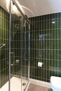 a green tiled bathroom with a shower and a toilet at The Bell Hotel, Saxmundham in Saxmundham