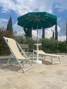 a pair of chairs and a green umbrella at Agriturismo Sant'Anna in Pomarance
