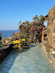 a patio with a yellow table and chairs and the ocean at Casa Nocilla, un dammuso sul mare! in Pantelleria