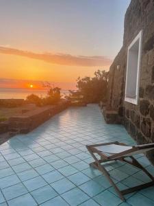 a patio with a bench and a sunset in the background at Casa Nocilla, un dammuso sul mare! in Pantelleria