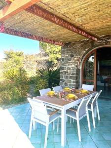 a table and chairs on a patio under a wooden roof at Casa Nocilla, un dammuso sul mare! in Pantelleria