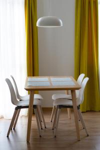 a wooden table with white chairs and a light fixture at Apartment next to Mall Plovdiv in Plovdiv