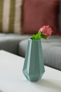 uma flor rosa num vaso azul sobre uma mesa em Apartment next to Mall Plovdiv em Plovdiv