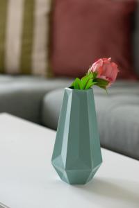 a pink flower in a blue vase on a table at Apartment next to Mall Plovdiv in Plovdiv