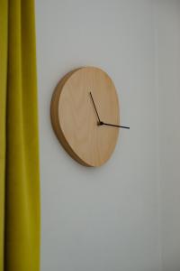 un reloj de madera colgado en una pared blanca en Apartment next to Mall Plovdiv en Plovdiv