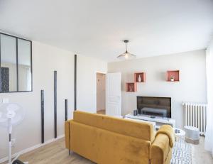 a living room with a yellow couch and a tv at Le Shopper - Confortable et Lumineux - Parking in La Chapelle-Saint-Luc