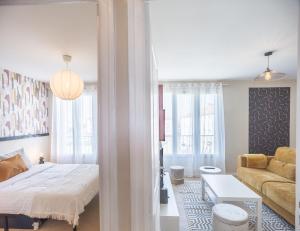 ein Schlafzimmer mit einem Bett und ein Wohnzimmer mit einem Sofa in der Unterkunft Le Shopper - Confortable et Lumineux - Parking in La Chapelle-Saint-Luc