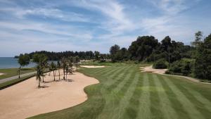 a view of a golf course with a beach and water at The Empire Brunei in Bandar Seri Begawan