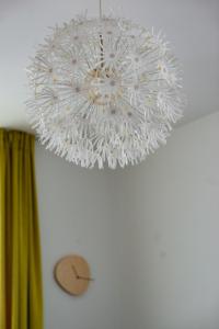 a white chandelier hanging from a ceiling with a clock at Apartment next to Mall Plovdiv in Plovdiv