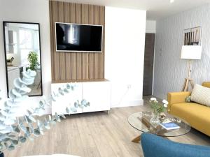 a living room with a couch and a tv at New Seaside Apartment 2 Porthcawl in Porthcawl