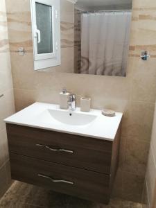 ein Badezimmer mit Waschbecken und Spiegel in der Unterkunft Comfy Apartment For 4 Ppl In Koukaki in Athen