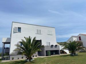 a white building with two palm trees in front of it at Holiday home " MIA" in Gradina