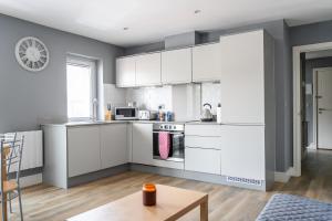 a kitchen with white cabinets and a table at Livestay-One Bed Apt in Slough with FREE Parking in Slough