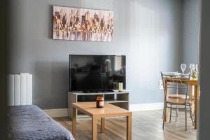 a living room with a flat screen tv and a table at Livestay-One Bed Apt in Slough with FREE Parking in Slough