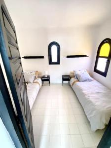 two beds in a room with two windows at Villa avec jardin sur la plage - Complexe Al Amine in Fnidek