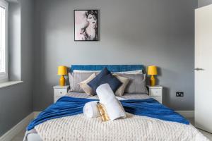 een slaapkamer met een groot bed met blauwe lakens en kussens bij Livestay-One Bed Apt in Slough with FREE Parking in Slough