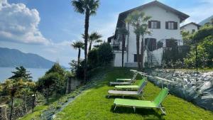 a row of chaise lounges on a lawn near a house at Diana Villa in Oggebbio