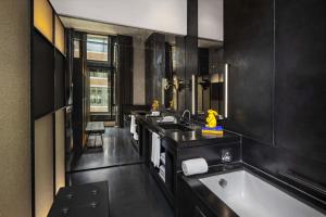 a black bathroom with a tub and a sink at W Amsterdam in Amsterdam
