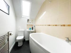 a bathroom with a tub and a toilet and a sink at One-Bedroom flat in Cheam Village in Cheam +17 photos
