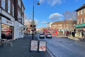 a city street with cars and buses on a street at One-Bedroom flat in Cheam Village in Cheam